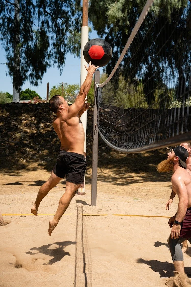 A Hoov Nation player jumping to throw a medicine ball over the net